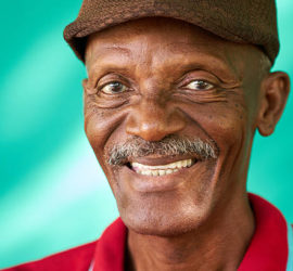 Real Cuban people and feelings, portrait of happy senior african american man looking at camera. Cheerful old latino grandfather with mustache and hat from Havana, Cuba